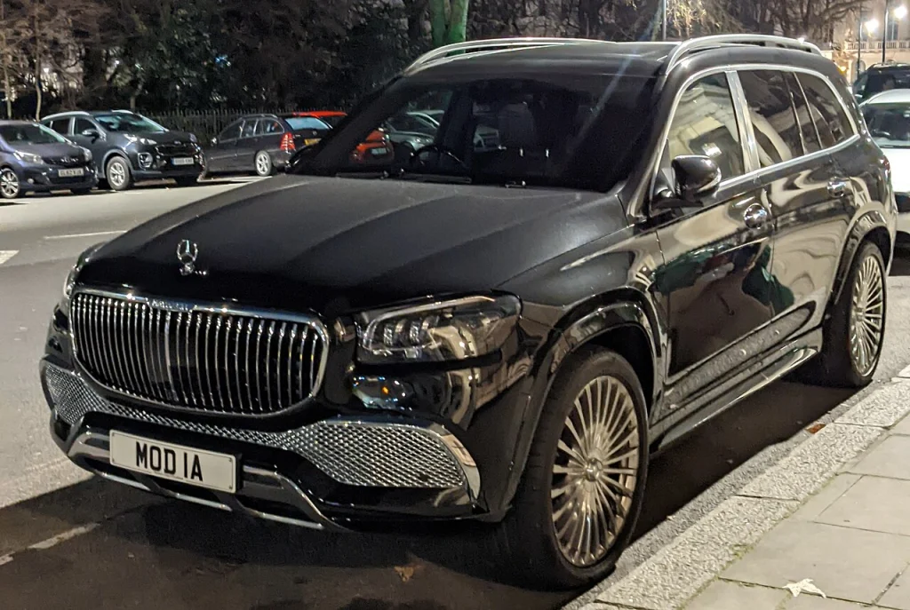 Dark Mercedes-Maybach GLS 600 parked beside a sidewalk at night