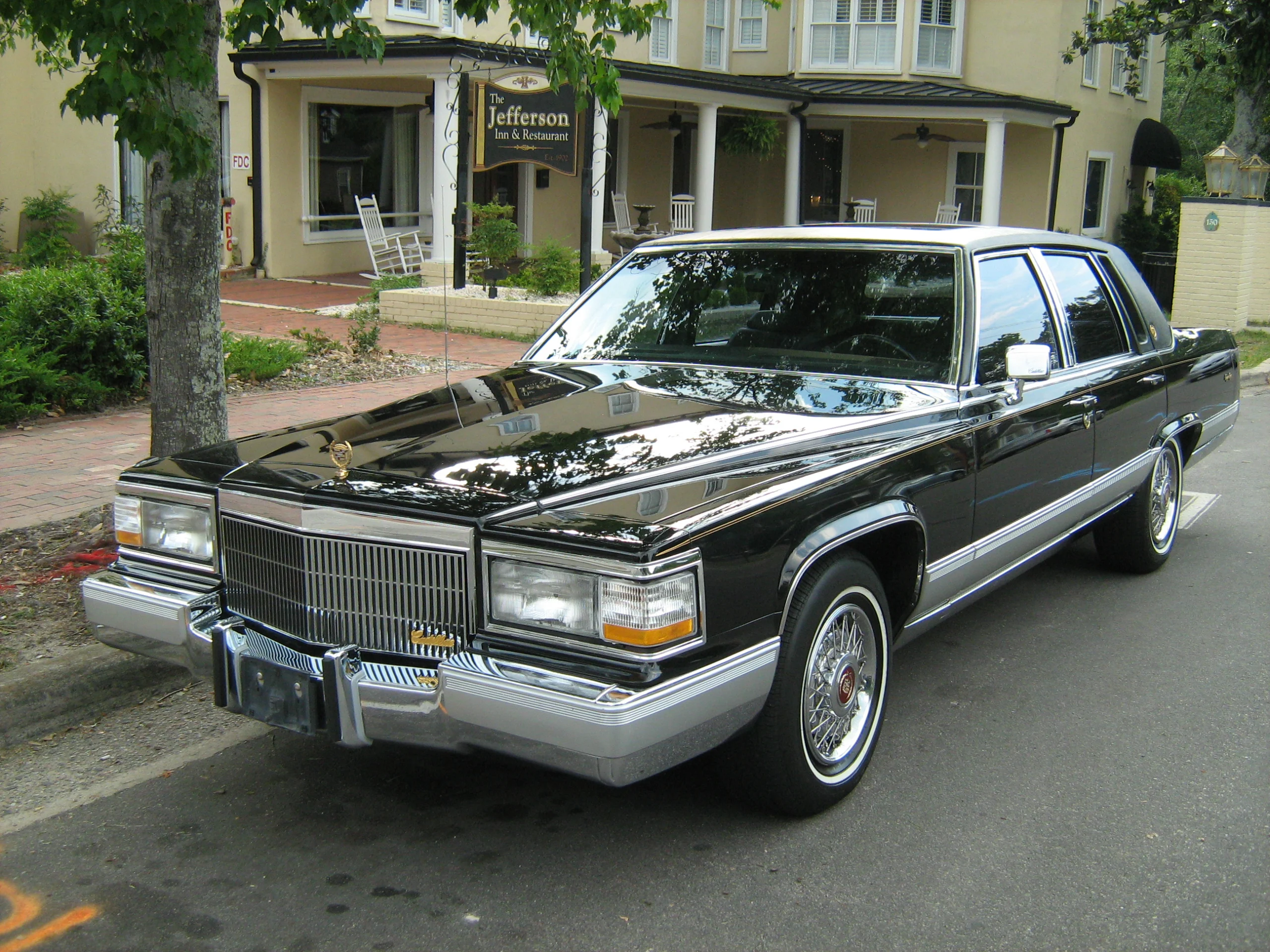 Black 1991 Cadillac Brougham sedan parked beside a sidewalk