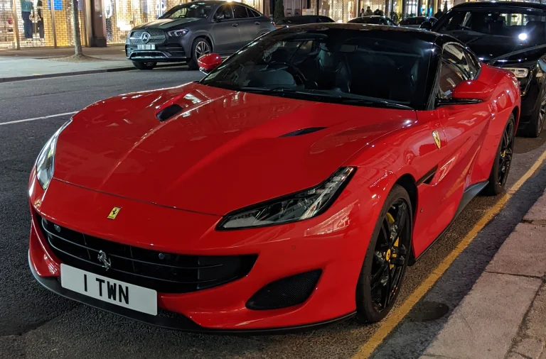 Red Ferrari Portofino with its roof raised, parked at night