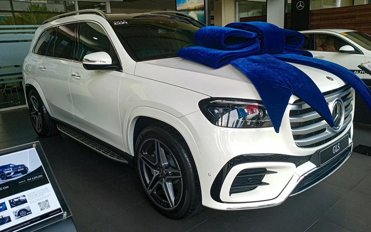White Mercedes-Benz GLS 450 with a blue gift bow on its hood