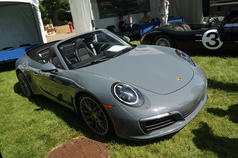 Gray Porsche 911 Carrera S Cabriolet with its roof lowered, displayed on grass